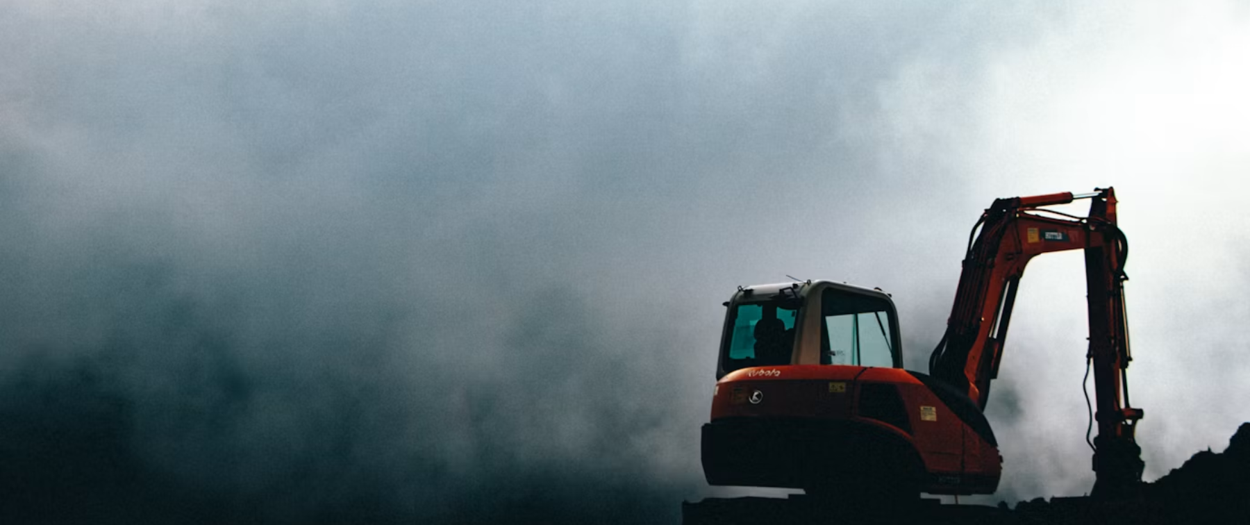 An excavator on a ridge in drifting fog