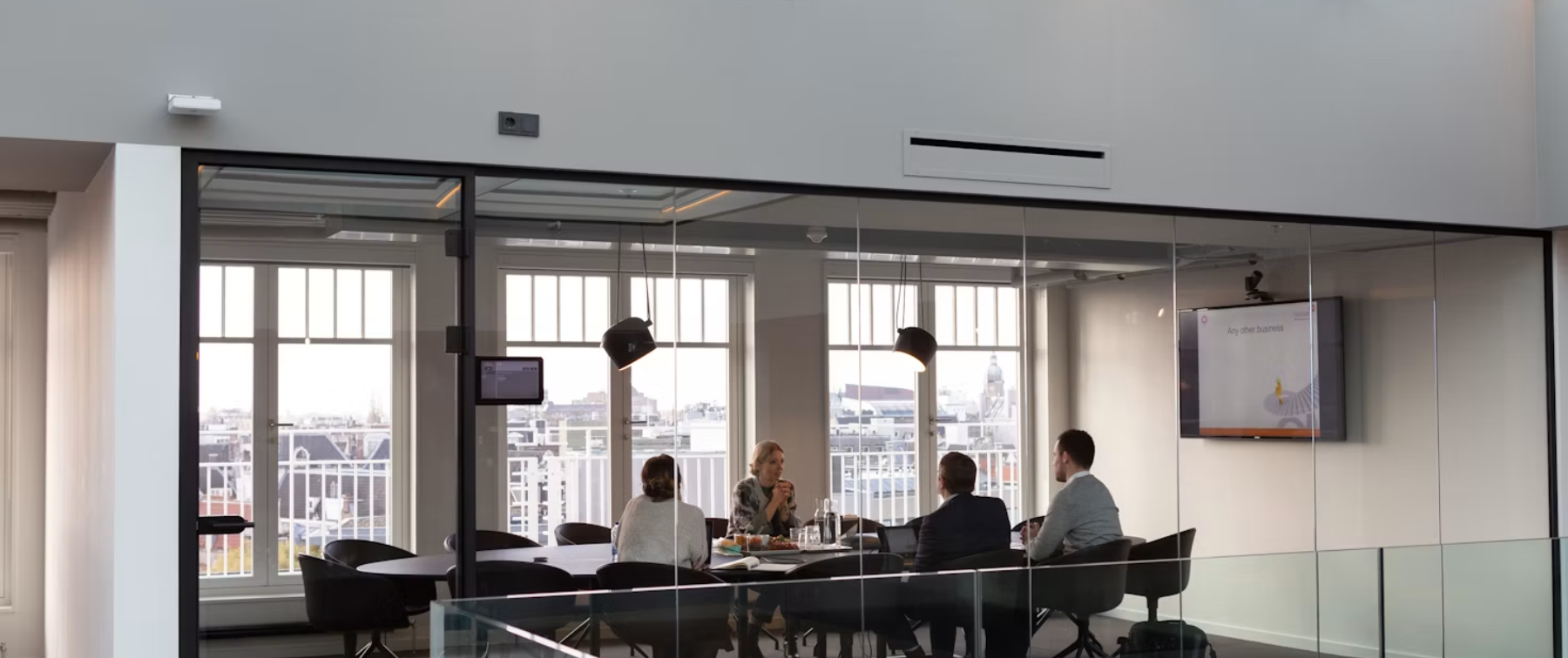 A team meeting in a glass-walled room, seen from the corridor
