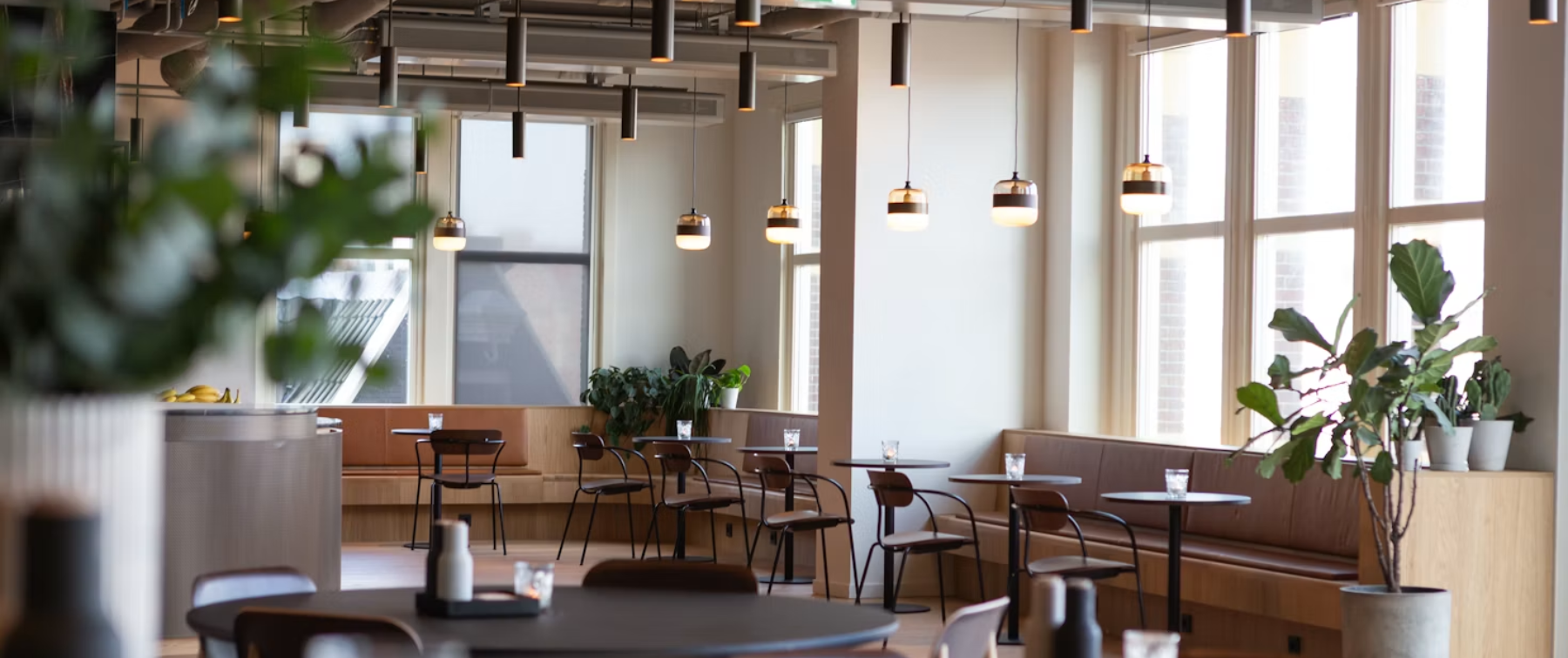An open-plan workspace with tables by tall windows