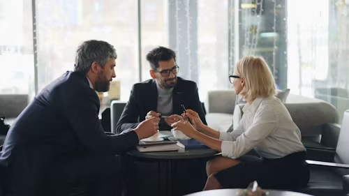 Three professionals discussing documents around a table